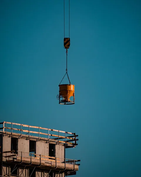 Concrete bucket suspended over a building under construction