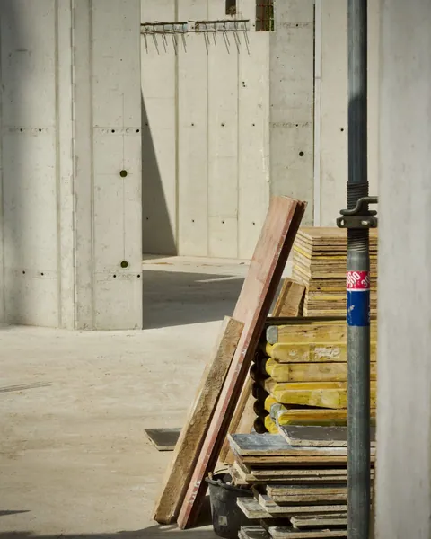 Building materials stacked beside a concrete wall under construction