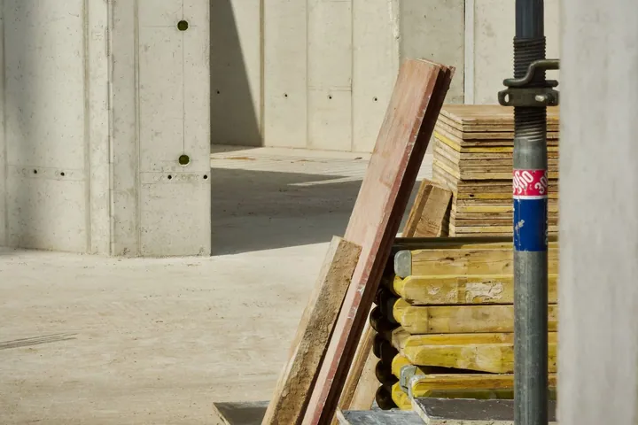 Building materials stacked beside a concrete wall under construction